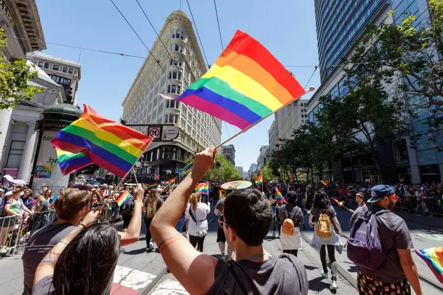 Menschen, die an der San Francisco Pride Parade teilnehmen, schwenken Regenbogenfahnen.